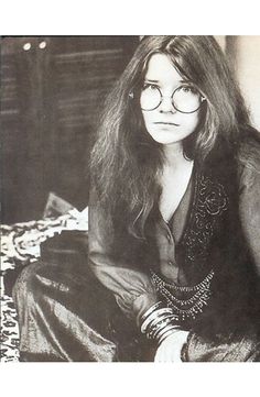 a woman sitting on top of a bed wearing glasses