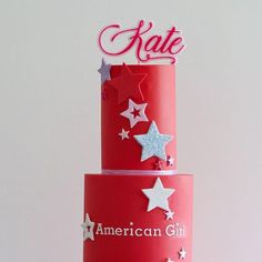 a three tiered red cake with stars on top and the word kate written on it