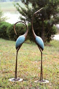 two metal flamingos are standing in the grass