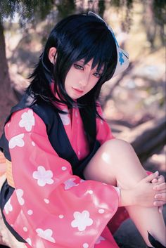 a woman in a pink and black kimono sitting on the ground