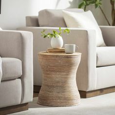 a table with two vases on it in front of a couch and coffee table