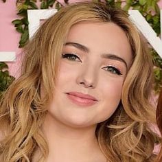 a close up of a person with blonde hair and blue eyeshadow wearing a black dress