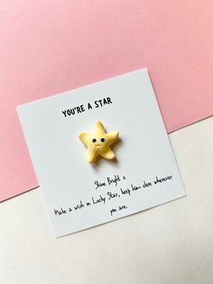 a yellow star brooch sitting on top of a piece of paper next to a pink wall