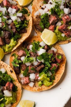 steak tacos with cilantro, lime and onions on a white platter