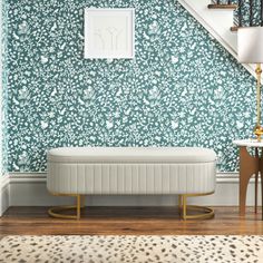 a white bench sitting under a stair case next to a wall with flowers on it