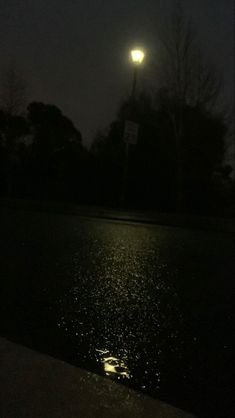 the street light shines brightly in the dark night sky over a puddle of water