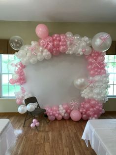 a balloon arch is decorated with pink and white balloons