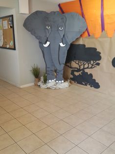 an elephant statue sitting on top of a tiled floor next to a large paper bag