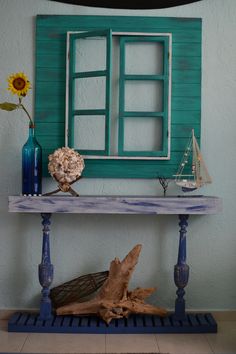 a blue table with a vase and sunflowers on it next to a window