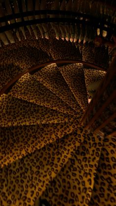 a spiral staircase made out of leopard print material is lit up by the light from below