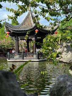 a gazebo in the middle of a pond surrounded by rocks