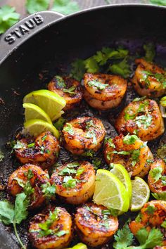 shrimp and limes in a skillet with garnishes on the side