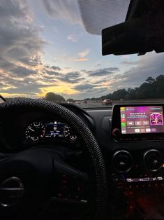 a car dashboard with the sun setting in the background