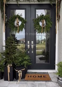 two christmas wreaths on the front door of a house with potted trees and presents