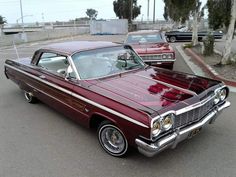 an old red car parked in a parking lot