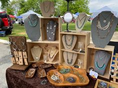 a table topped with lots of necklaces and wooden boxes filled with different types of jewelry