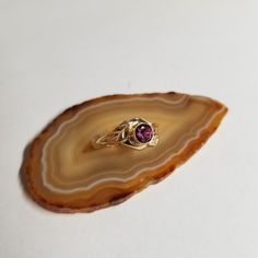 This is a one of kind cast ring in 14kt yellow gold. It has a 5.5mm round purple genuine sapphire that is bezel set. The shank comes up into two leaf designs that surround the stone. The ring is a size 7. Heirloom Amethyst Ring In Yellow Gold With Bezel Setting, Heirloom Gold Amethyst Ring With Bezel Setting, Heirloom 14k Gold Amethyst Ring With Bezel Setting, Gold Solitaire Amethyst Ring, Gold Amethyst Solitaire Ring, Gold Amethyst Birthstone Ring Heirloom Style, Gold Heirloom Amethyst Ring, Heirloom Gold Amethyst Birthstone Ring, Gold Amethyst Birthstone Ring With Bezel Setting