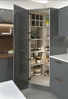 an open pantry in the middle of a kitchen with white counter tops and gray cabinets