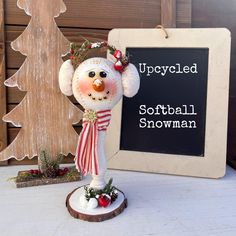 a snowman statue sitting next to a sign that says upcycled softball snowman