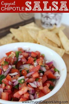 a white bowl filled with salsa next to tortilla chips on top of a wooden table