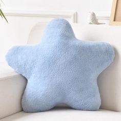 a blue star pillow sitting on top of a white couch next to a potted plant