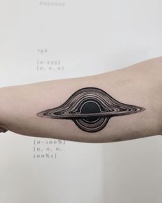 a black and white image of a saturn tattoo on the left arm, with space in the middle