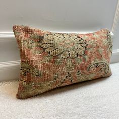 a decorative pillow sitting on the floor next to a white wall with a door in it