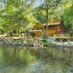 a house sitting on top of a lush green forest next to a river