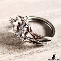 a silver ring with flowers on it sitting on a counter top in front of a white background