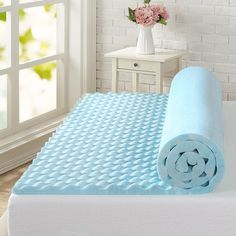 a rolled up blue mattress in front of a window