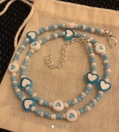 a blue and white beaded necklace with hearts on it, sitting on a bag