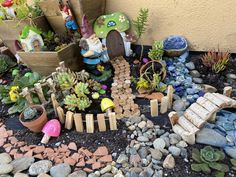 an assortment of plants and rocks on the ground near a wall with a gnome's house in it