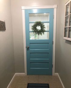 a blue front door with a wreath on the top and side glass window above it