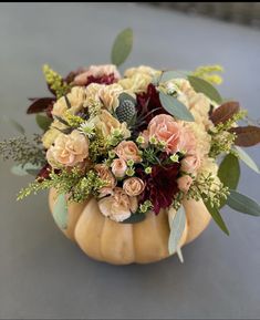 a vase filled with flowers and greenery on top of a table