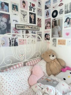 a teddy bear sitting on top of a bed next to a wall with many pictures