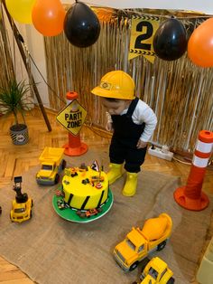 a young boy standing in front of a construction themed cake