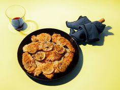 a black plate topped with fried food next to a glass of wine