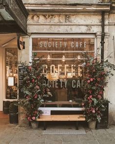 a wooden bench sitting in front of a building with flowers growing out of it's windows