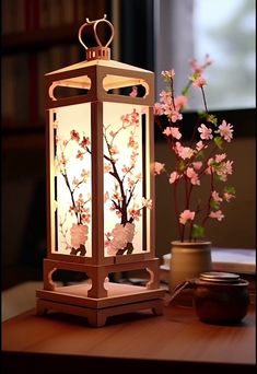 a lantern with flowers on it sitting on a table next to a potted plant