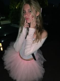 a woman in a pink tutu posing for the camera with her hand on her face