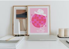 a laptop computer sitting on top of a white desk next to a pink poster with a cowboy hat