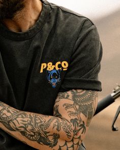 a man with tattoos on his arm holding a cell phone and looking at the camera