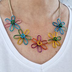 Bold floral necklace handmade in the UK. This eye-catching necklace consists of five wire flowers in lovely bright colours. The wire changes colour along its length and each flower is hand formed from coated aluminium so no two will be exactly the same! Dare to make a statement with this unique necklace. I will make your necklace to order, feel free to message me if you have any specific requests regarding flower colours. The flowers hang from a neutral colour faux suede cord. Total length is ap Multicolor Necklaces With Handmade Flowers For Gift, Multicolor Flower Choker As Gift, Handmade Multicolor Flower Necklaces, Handmade Multicolor Flower Pendant Necklace, Whimsical Multicolor Flower Shaped Jewelry, Adjustable Multicolor Flower Necklace, Vase Necklace, Unique Multicolor Flower Pendant Necklace, Unique Multicolor Flower Necklace