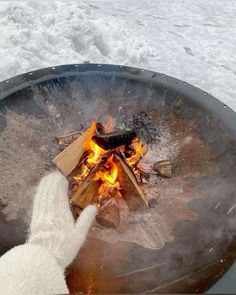 a person in white gloves roasting marshmallows over an open fire pit