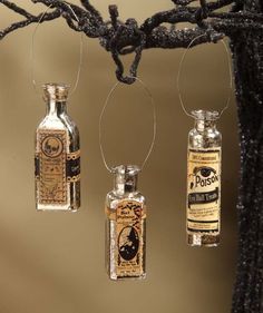 three miniature bottles are hanging from a tree