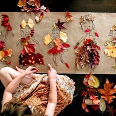 two children are playing with autumn leaves and paper dolls on the floor next to them