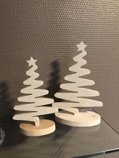 two wooden christmas trees sitting on top of a glass table