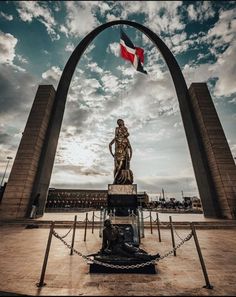 the statue is in front of an arch with a flag on it and a chain around it