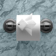 a toilet paper holder with an origami fish on it's side, mounted on a marble wall