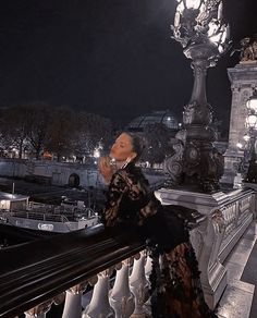 a woman standing on top of a balcony next to a street light and clock tower